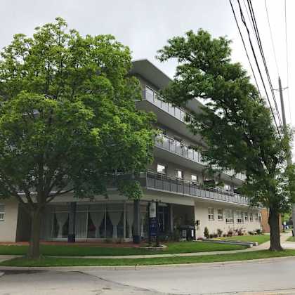 a tree in front of a building with a balcony.