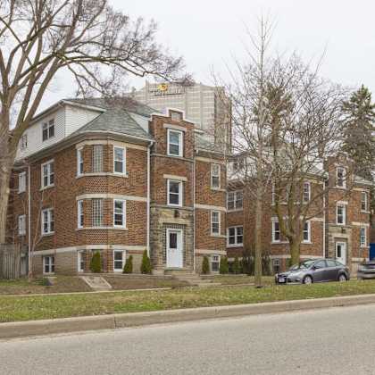 a large brick building with a green roof sits on a street corner.