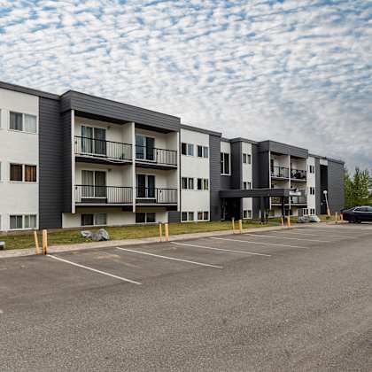 a parking lot in front of a multi-story apartment building.