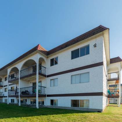 a white and brown building with balconies and a red roof.