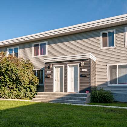 a grey house with a white door and windows.