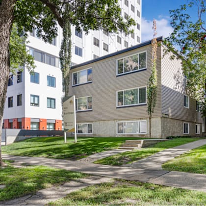 a tree-lined street with apartment buildings on either side.