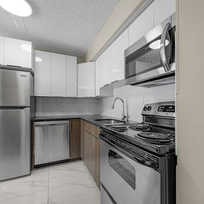 a modern kitchen with stainless steel appliances and white cabinets.