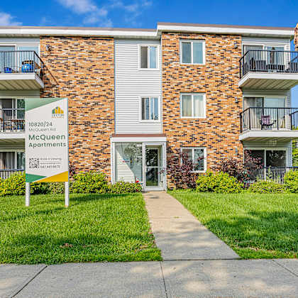 the image shows a mcqueen apartments sign in front of a multi-story building.