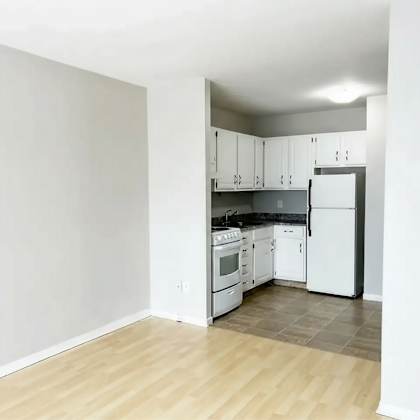 a kitchen with white appliances and wooden floors.