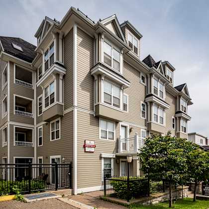 a large, multi-story residential building with a black fence in front.