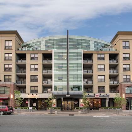 a large building with a glass center and a red car in front of it.