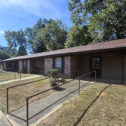 a small building with a brown roof and a metal fence in front of it.
