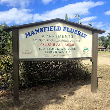 a sign for mansfield elderly apartments with contact information.