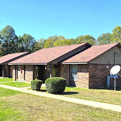 a house with a red roof and satellite dishes on the lawn.