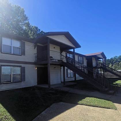 a sunny day at a two-story house with a balcony and a staircase.