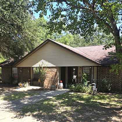 a house with a brown roof and a white garage door is surrounded by trees.