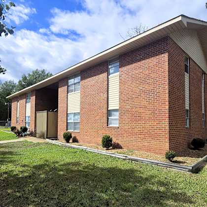 a small red brick building with a white roof and a small porch.