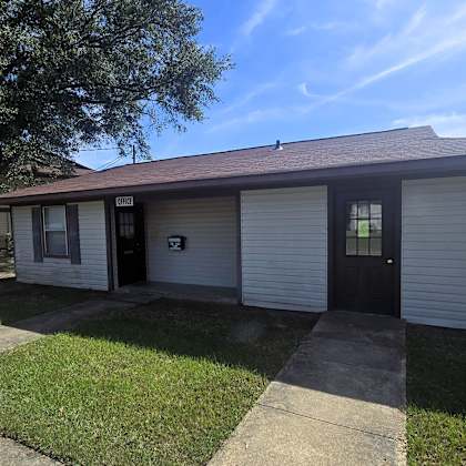 a small white house with a brown roof and a black door.