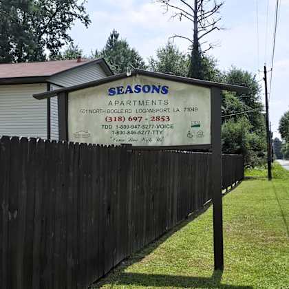 a sign for seasons apartments is displayed on a fence.