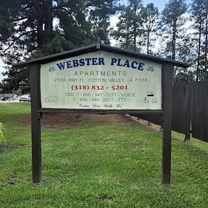 a sign for webster place apartments is displayed in a grassy area.