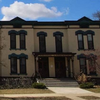a large, two-story building with a dark brown door and windows on the second floor.