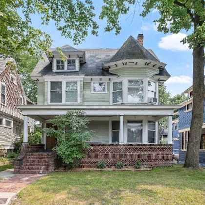 a victorian style house with a grey front porch.