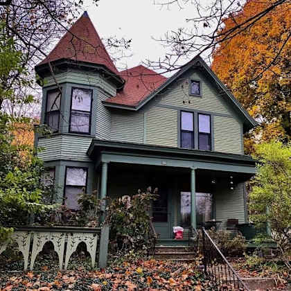 a green house with a red roof and a porch.