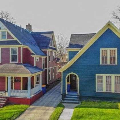 a blue house with a red house in the background.