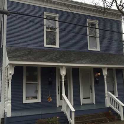 a blue house with white trim and a front porch.