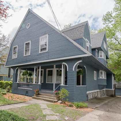 a blue house with a porch and a front yard.