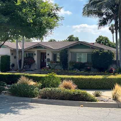 a house with a white fence and a tree in front.