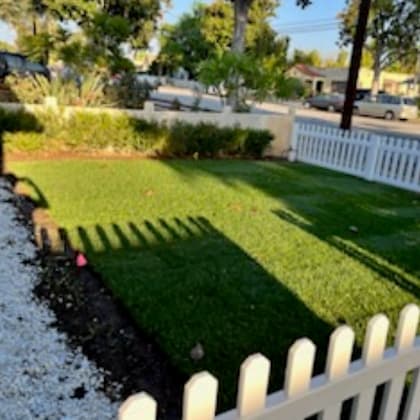 a white picket fence borders a green lawn.