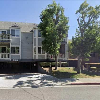 a large house with a balcony and a tree in front.