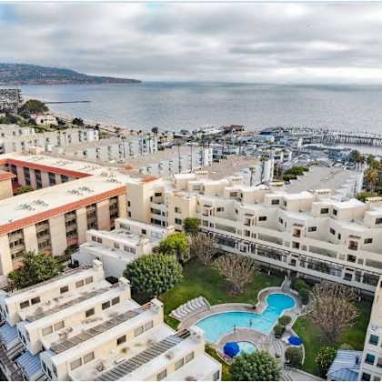 a large white building with a red roof is surrounded by a pool and a view of the sea.