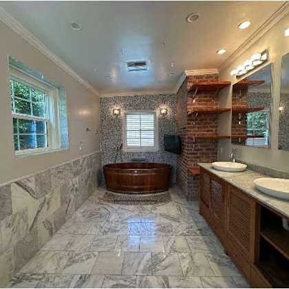 a bathroom with a marble floor and a brick wall.