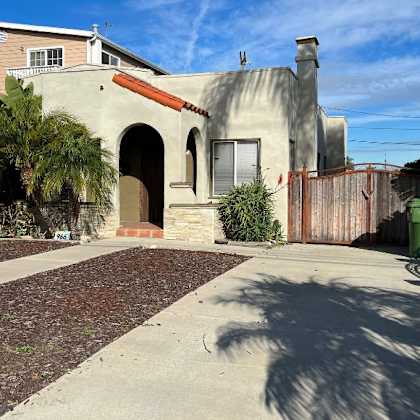 a house with a brown roof and a white wall with a window and a door.