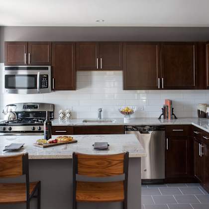 a kitchen with a white counter top and wooden chairs.