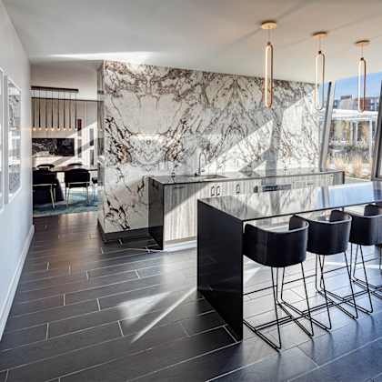 a modern dining room with a marble wall and black chairs.