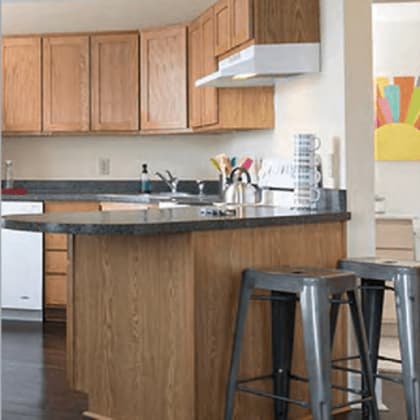 a kitchen with wooden cabinets and a bar stool.