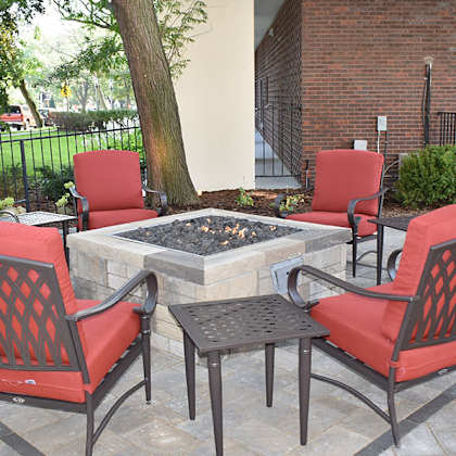 a patio with a fire pit and chairs.