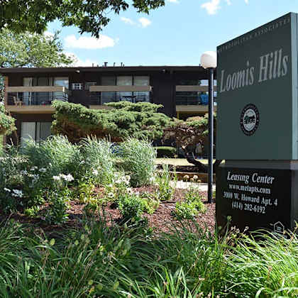 a sign for loomis hills leasing center stands in front of a building.