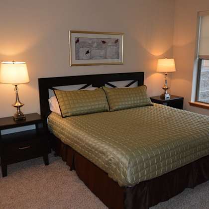 a bedroom with a bed, nightstands, and a window.