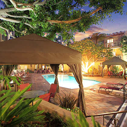a poolside area with a tent and chairs is lit up at night at mediterranean village west hollywood, west hollywood, 90069