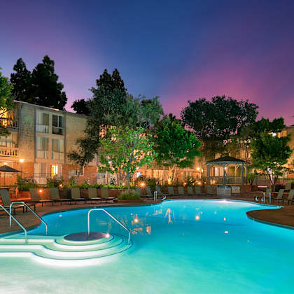 a swimming pool with a few people in it at night at the meadows apartments, culver city , ca 90230