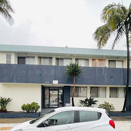a building with a black roof and palm trees in front of it