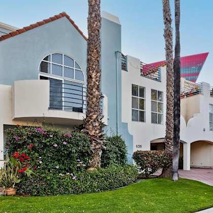 a blue and white house with palm trees in front of it