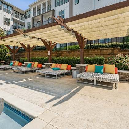 a group of lounge chairs under a large canopy next to a pool at beckett farms apartments, prg real estate management, fort mill, 29715