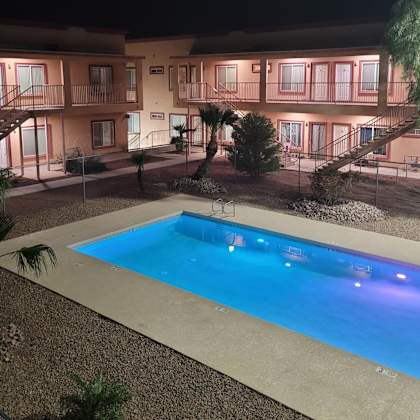 a swimming pool in front of a building at night.