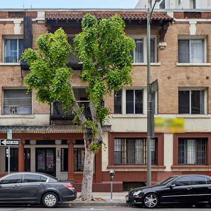 two cars parked in front of a building with a tree in between.