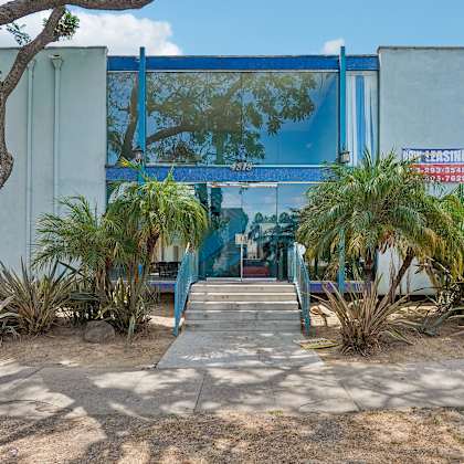a blue building with a glass window and a red sign on it.