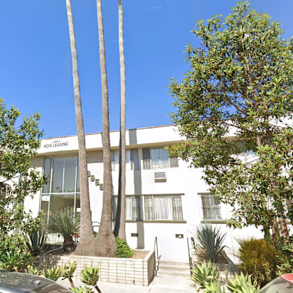 a white building with a red car parked in front.
