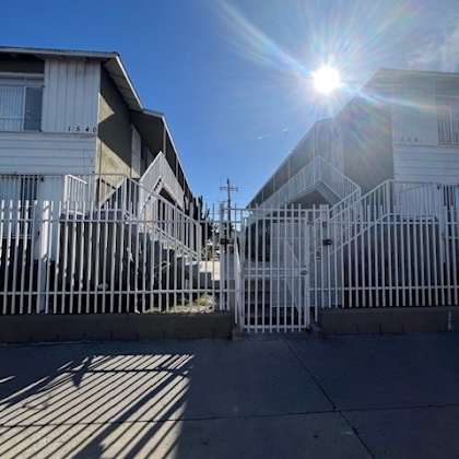 a sunny day in front of a row of houses with a bright sun in the sky.
