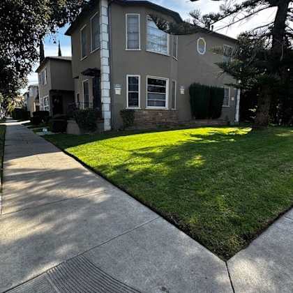 a house with a well-kept lawn and a sidewalk in front.