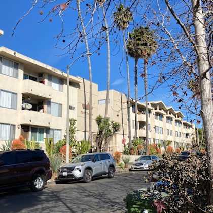 a row of apartment buildings with cars parked in front.
